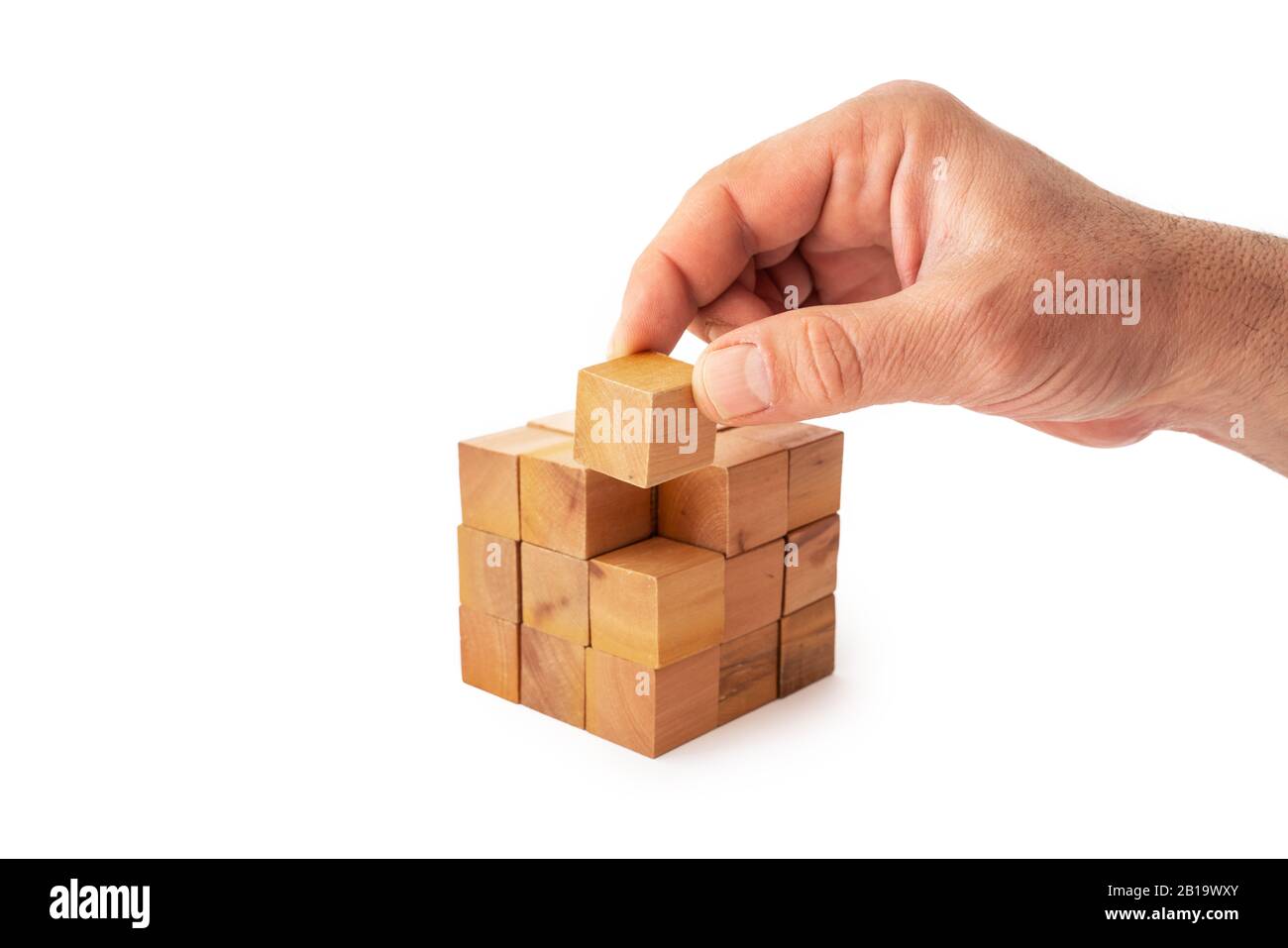 Une main met le dernier cube pour construire un cube avec des cubes en bois sur fond blanc. Succès, stratégie, travail d'équipe et concept de victoire Banque D'Images