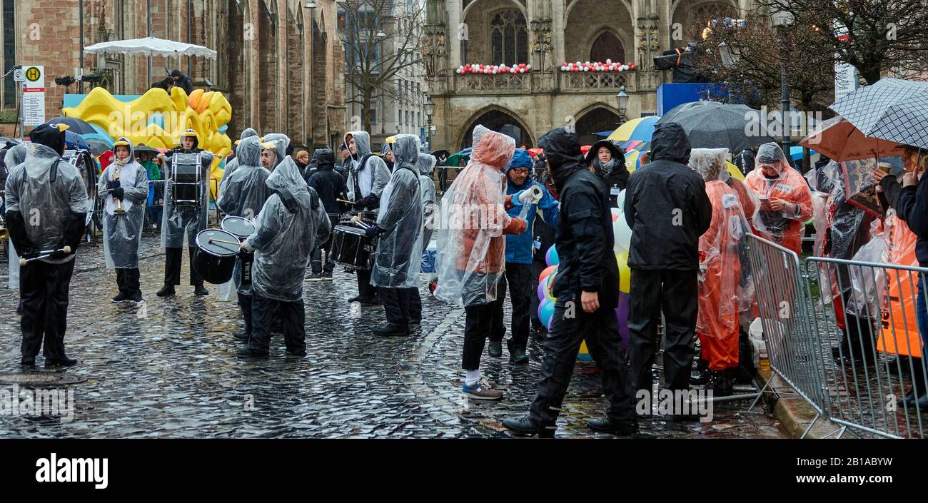 Braunschweig, Allemagne, 23 février 2020: Troupe de musique avec batterie et spectateurs en tenue de pluie avant le début de la procession du carnaval Banque D'Images