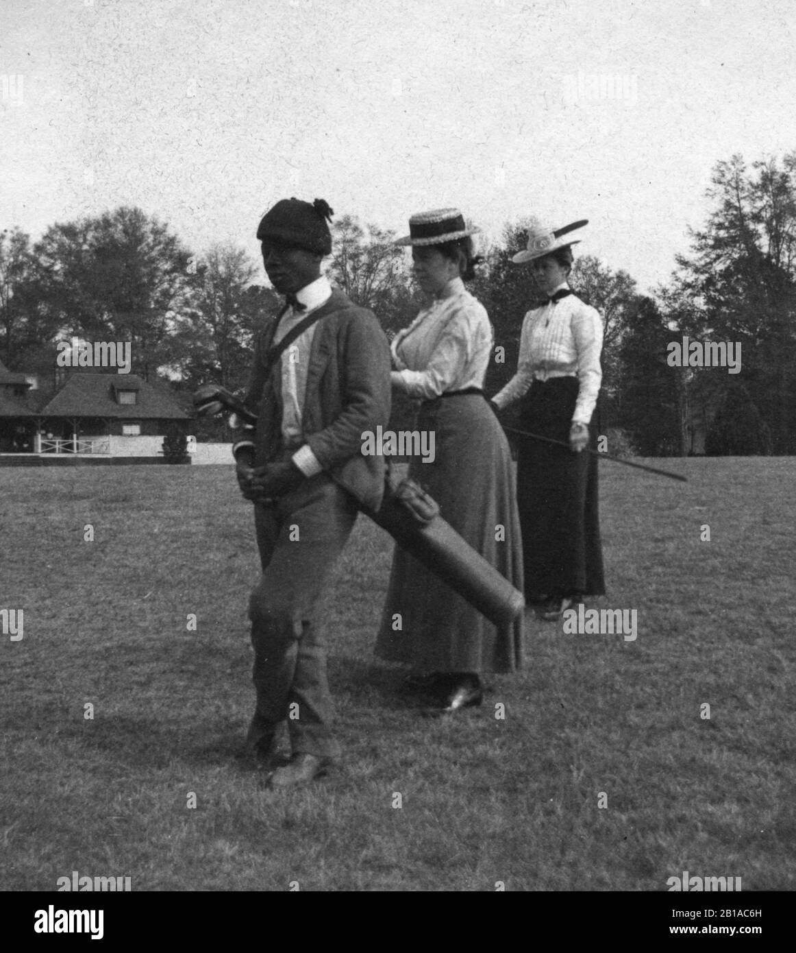 Golf: African American Caddy et 2 femmes blanches golfeurs stand, attendant un autre golfeur. Caddy a un sac de golf mince suspendu de son épaule. Le pavillon est en arrière-plan. Photo c.1910 pour voir mes autres images vintage liées au golf, recherche: Prestor vintage sport African Banque D'Images