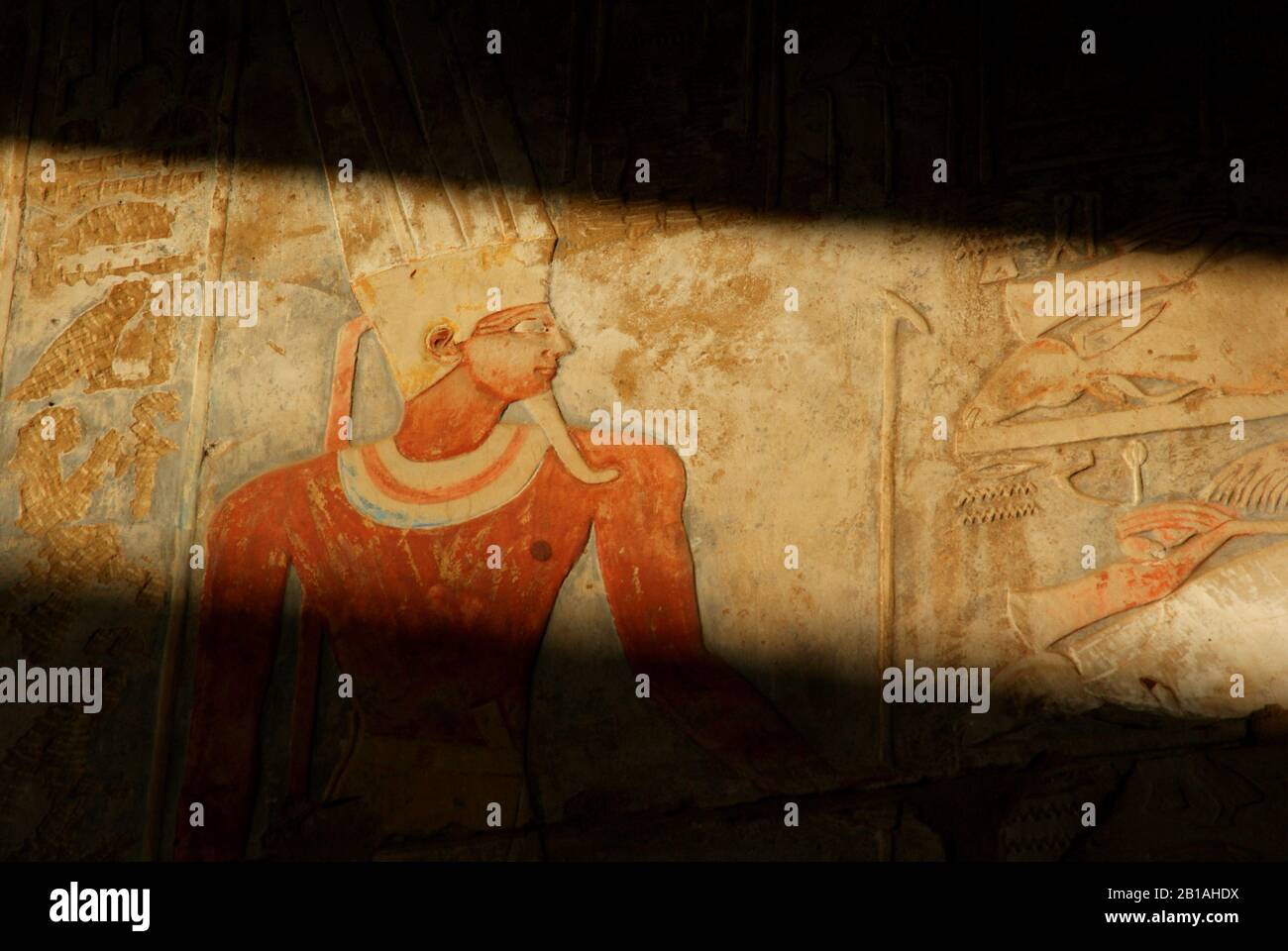 Une chaîne de lumière qui brille sur une ancienne peinture murale montrant un pharaou en Égypte Banque D'Images
