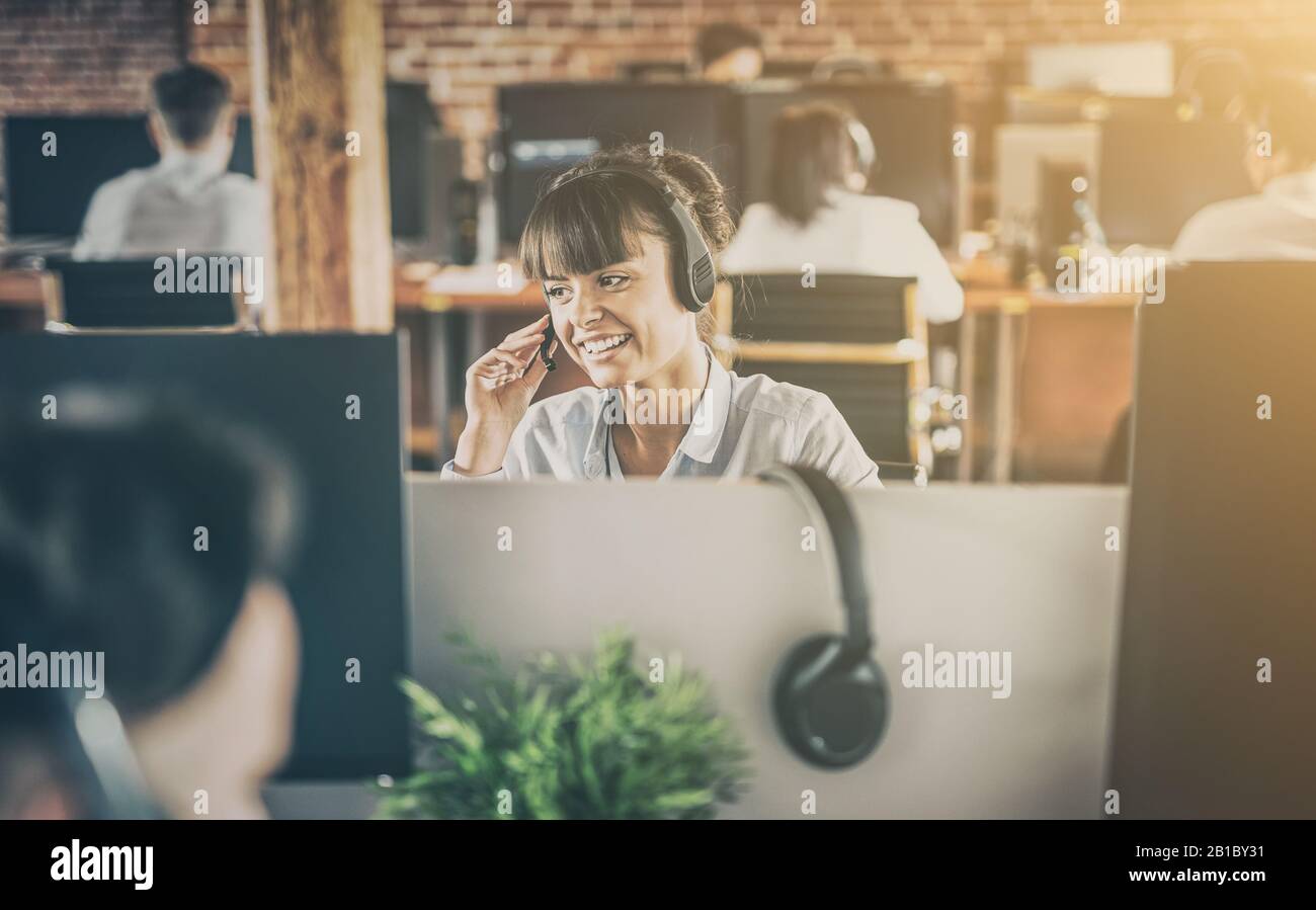 Travailleur de centre d'appel, accompagnée par son équipe. Smiling customer support au travail de l'opérateur. Jeune employé de travailler avec un casque. Banque D'Images