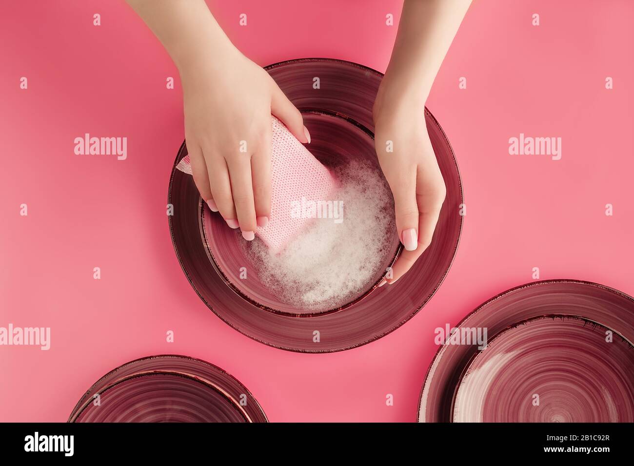 Les mains féminines se lavent de belles plaques en céramique sur un fond rose tendance. Concept de minerais ménagers. Toile de fond pour votre conception. Style plat. Copier l'accélérateur Banque D'Images