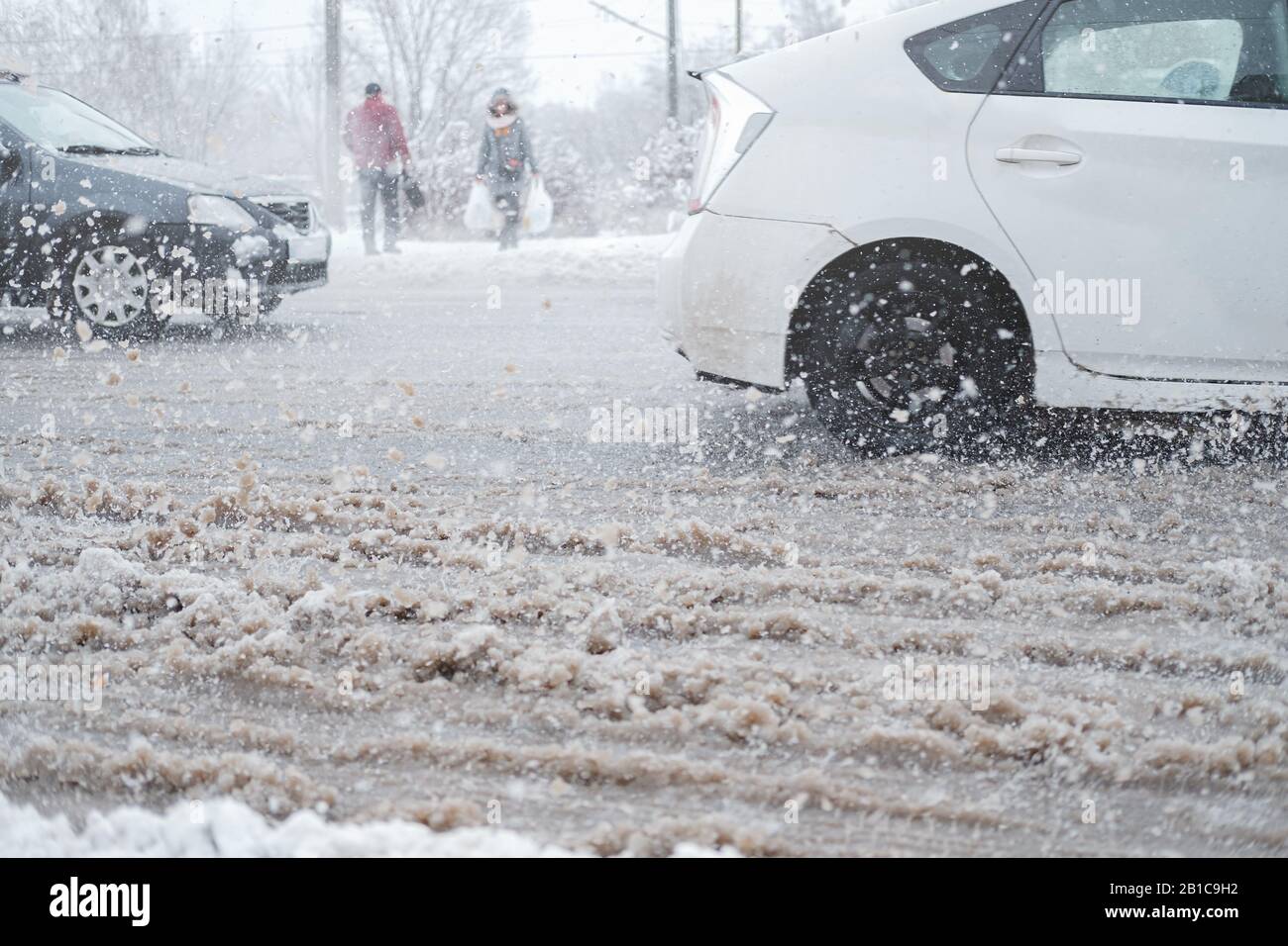 Trafic urbain dans la tempête de neige, flou de mouvement. Les voitures traversent une route désordonnée non nettoyée, concept de sécurité routière dans les mauvaises conditions météorologiques Banque D'Images