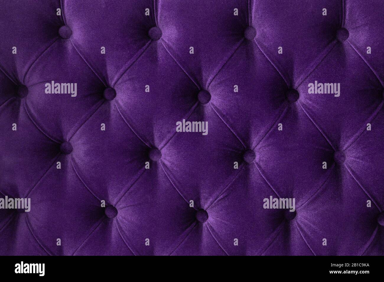 Tissu en velours ouatiné violet de couleur pourpre boutonné motif mural arrière-plan. Élégant canapé-lit de luxe vintage. Intérieur en toile de fond Banque D'Images