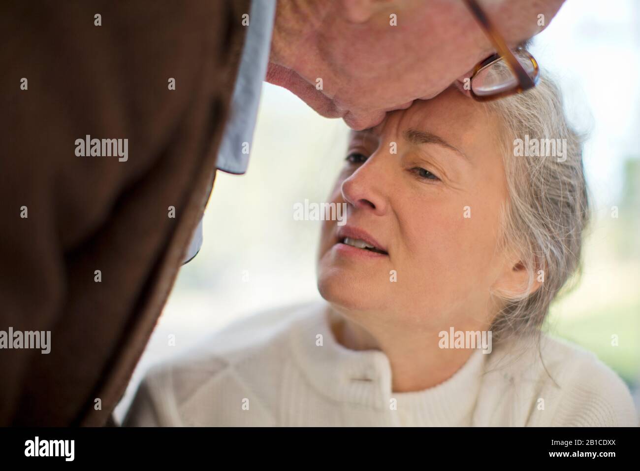 Senior femme malheureuse d'être embrassé sur le front de son mari. Banque D'Images