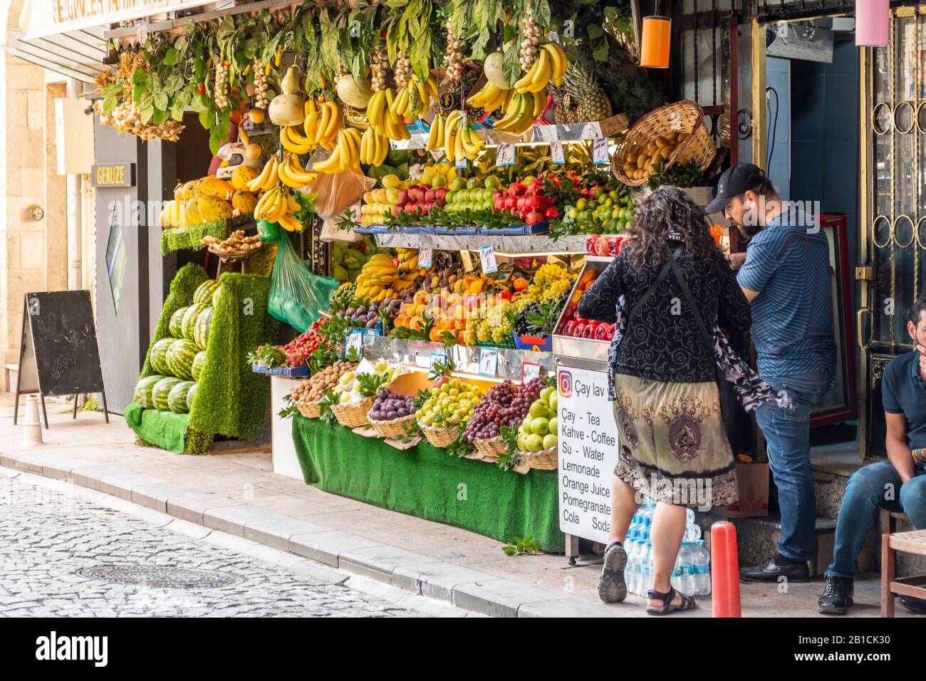 Une femme achète des fruits frais auprès d'un vendeur de rue qui vend des produits et des jus à Istanbul, en Turquie. Banque D'Images