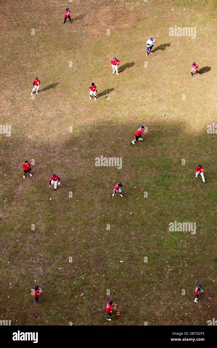 Un groupe de joueurs de base-ball portant un maillot rouge pratique leur compétence de pichet de balle sur le terrain d'un point de vue aérien. Banque D'Images