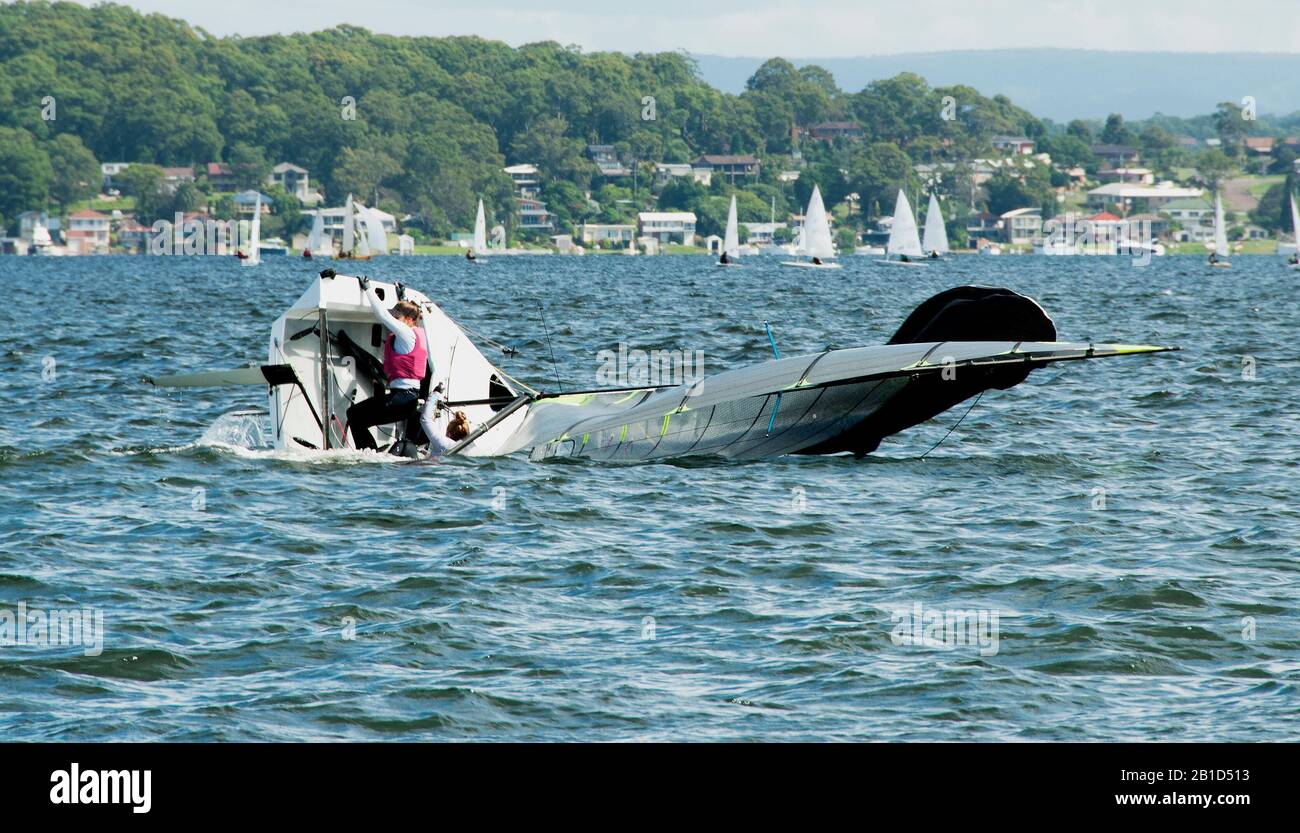 Un marin junior grimpant à bord d'un voilier de taille caprice pendant une régate de voile de l'école secondaire. Les enfants s'y courses au lac d'eau salée Macquarie. Po Banque D'Images