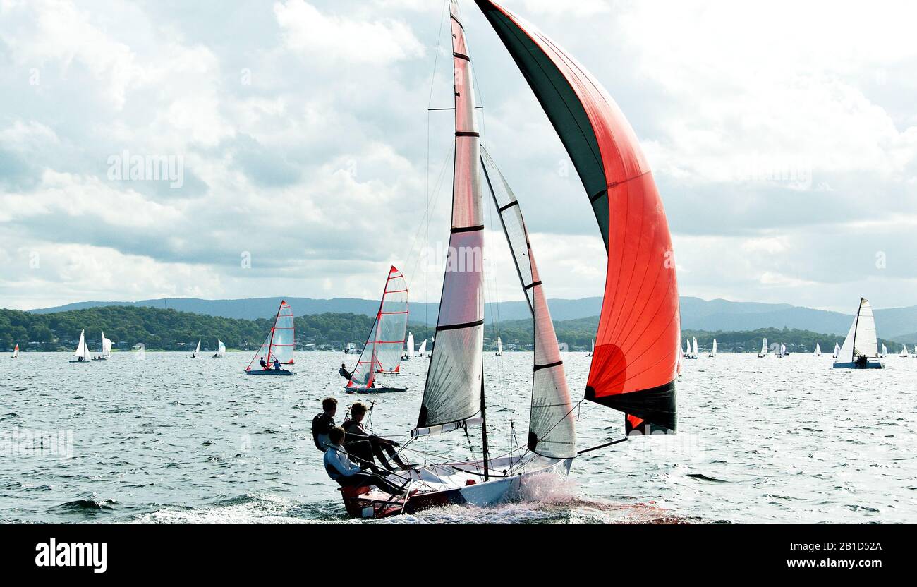 Les enfants qui naviguent dans de petits bateaux colorés et des dinghies pour s'amuser et en compétition. Travail d'équipe par des marins juniors en course sur le lac Macquarie Banque D'Images