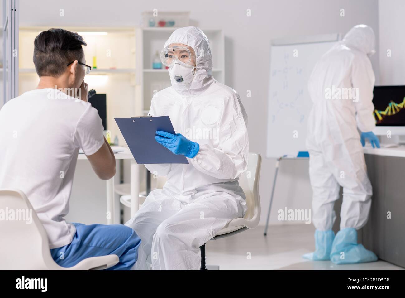 Spécialiste médical en cas de risque biologique et respirateur demandant aux patients coronavirus des symptômes Banque D'Images