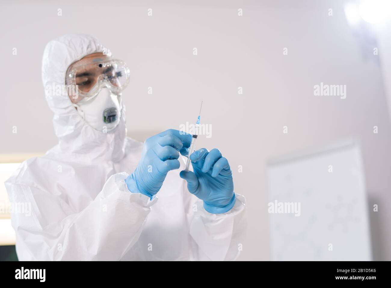 Spécialiste médical en combinaison de protection utilisant une seringue tout en vaccinant les personnes contre les virus dangereux Banque D'Images