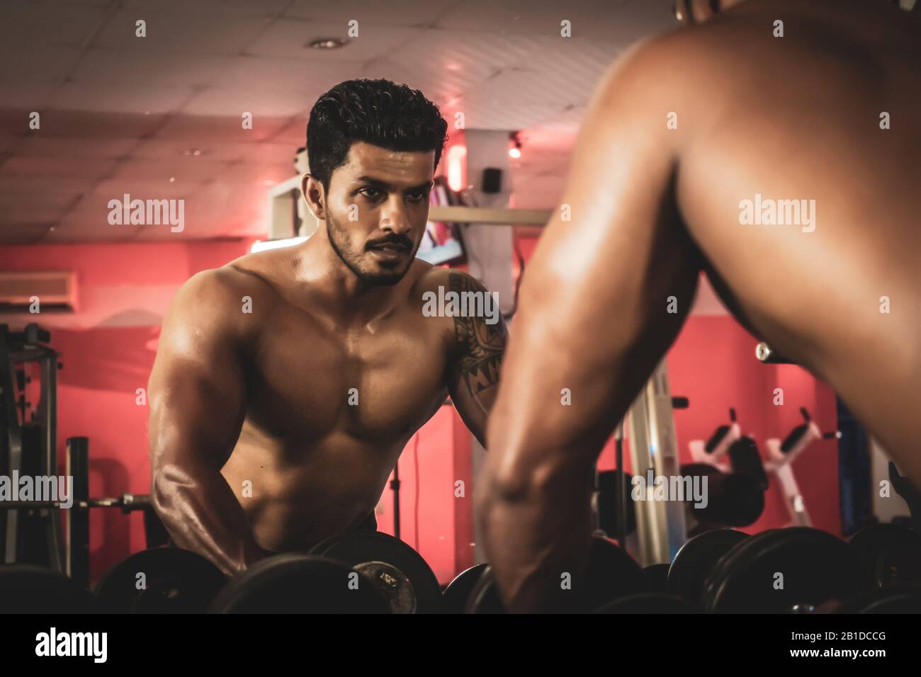 l'homme debout devant un miroir prend des haltères dans la salle de gym Banque D'Images