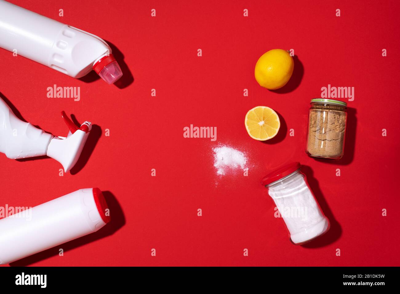 Bicarbonate de soude, poudre de citron et de moutarde contre les produits chimiques ménagers sur fond rouge. Vue de dessus. Espace de copie. Pose plate. Nettoyage efficace et sûr de la maison. Banque D'Images