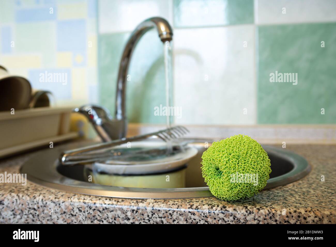 Tampon à récurer en plastique vert, utilisé pour nettoyer les plats, les assiettes, les casseroles et les pots, près de l'évier dans la cuisine. Banque D'Images
