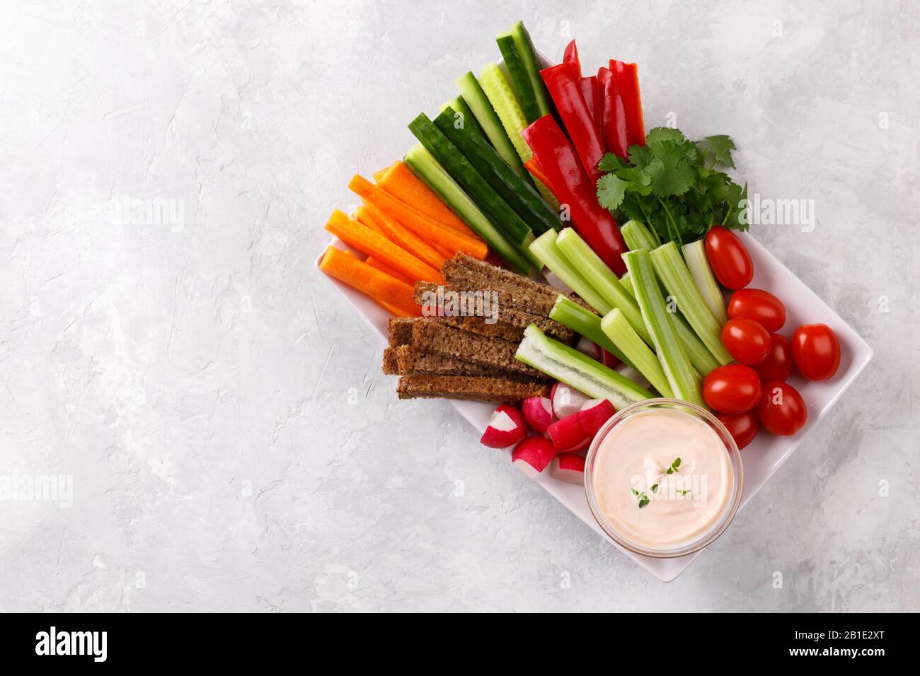 En-cas de légumes sains avec sauce au yaourt sur fond de pierre grise, vue de dessus rapprochée, espace de copie Banque D'Images