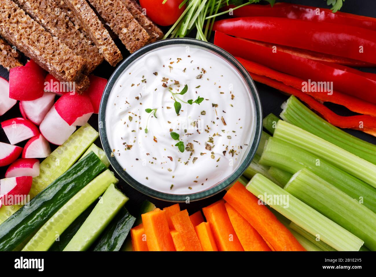 En-cas de légumes sains avec sauce au yaourt sur une planche ronde en pierre d'ardoise, vue de dessus rapprochée Banque D'Images