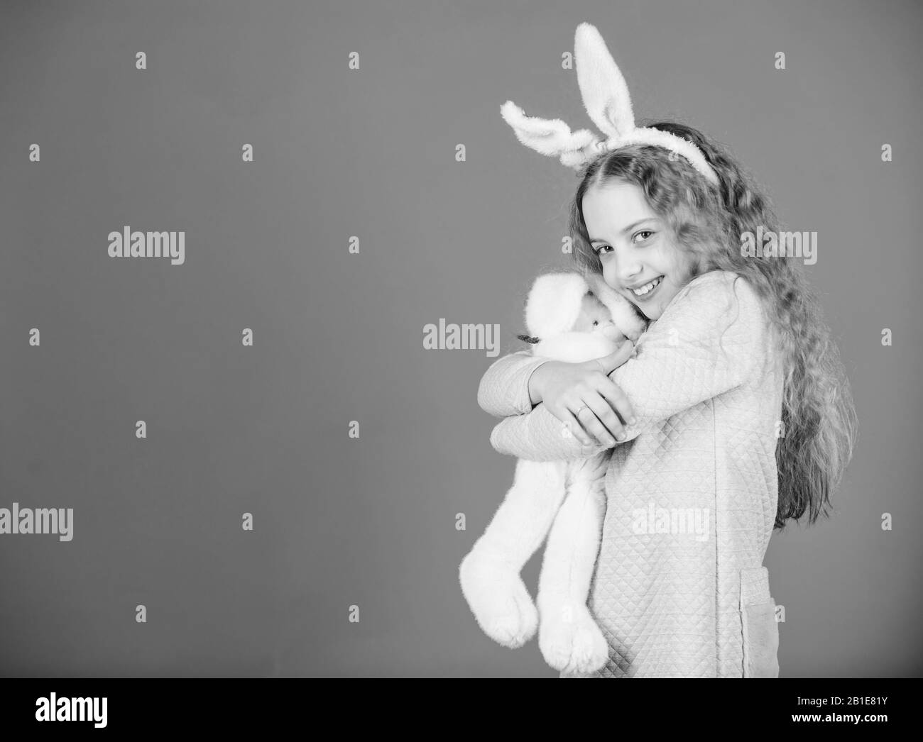 Avec mignon lapin jouet sur fond bleu. Sourire de l'enfant jouer bunny jouet. Enfance heureuse. Obtenez dans l'esprit de Pâques. Oreilles de lapin accessoire. Joli lapin enfant espiègle aux cheveux longs. Mignon et adorable. Banque D'Images