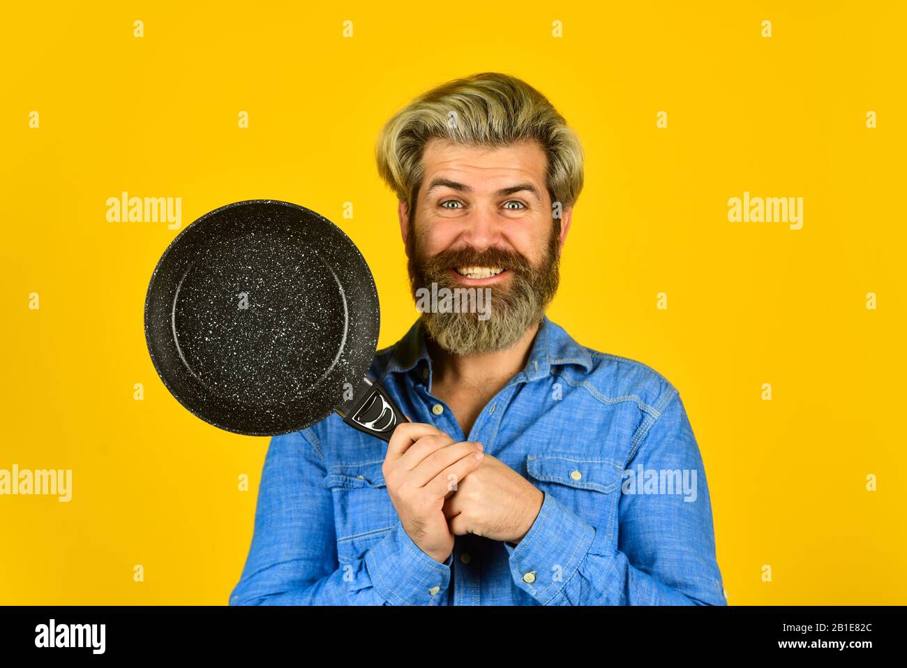 Poêle antiadhésive pour la friture. Récipients de cuisson émaillés. L'homme tient la poêle. Friture. Des aliments sains. Hipster barbu préparant le petit déjeuner. Parfait pour les crêpes. Frire sans huile. ustensiles de cuisine professionnels. Banque D'Images