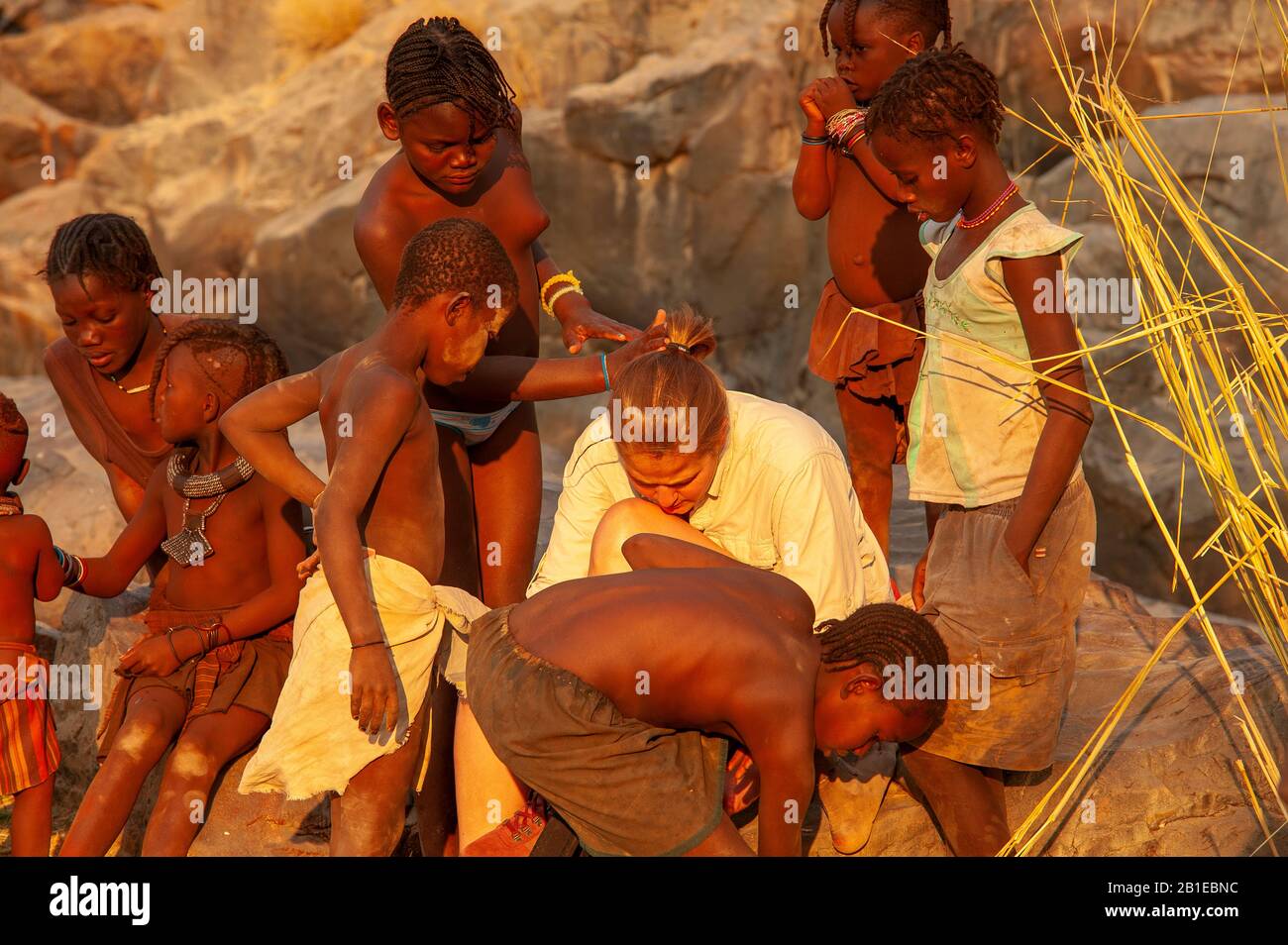 Femme européenne socialisant avec les enfants de la tribu himba à Epupa Falls, région de Kunene, Namibie Banque D'Images