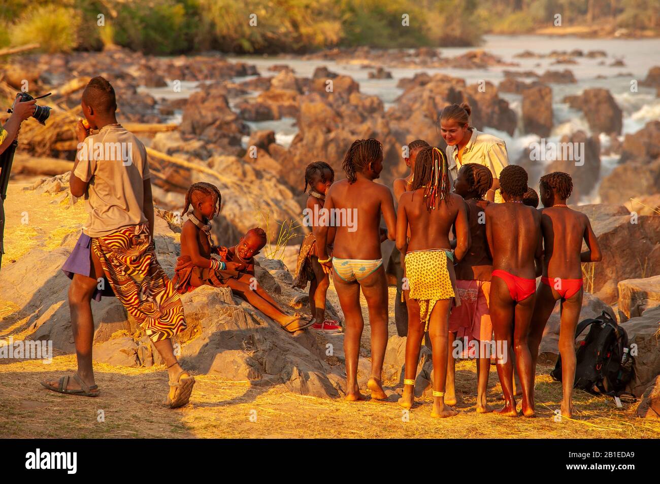 Femme européenne socialisant avec les enfants de la tribu himba à Epupa Falls, région de Kunene, Namibie Banque D'Images