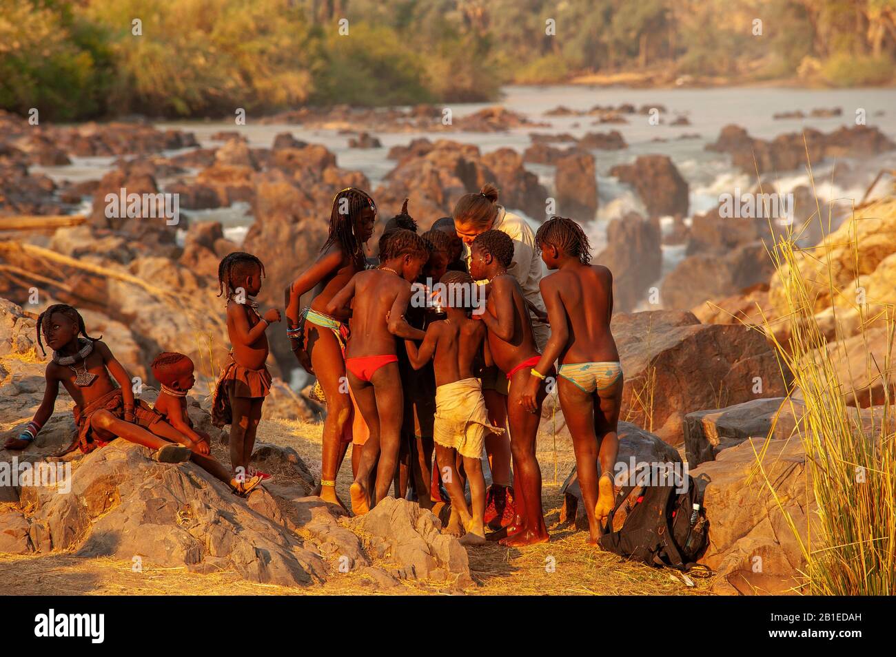 Femme européenne socialisant avec les enfants de la tribu himba à Epupa Falls, région de Kunene, Namibie Banque D'Images