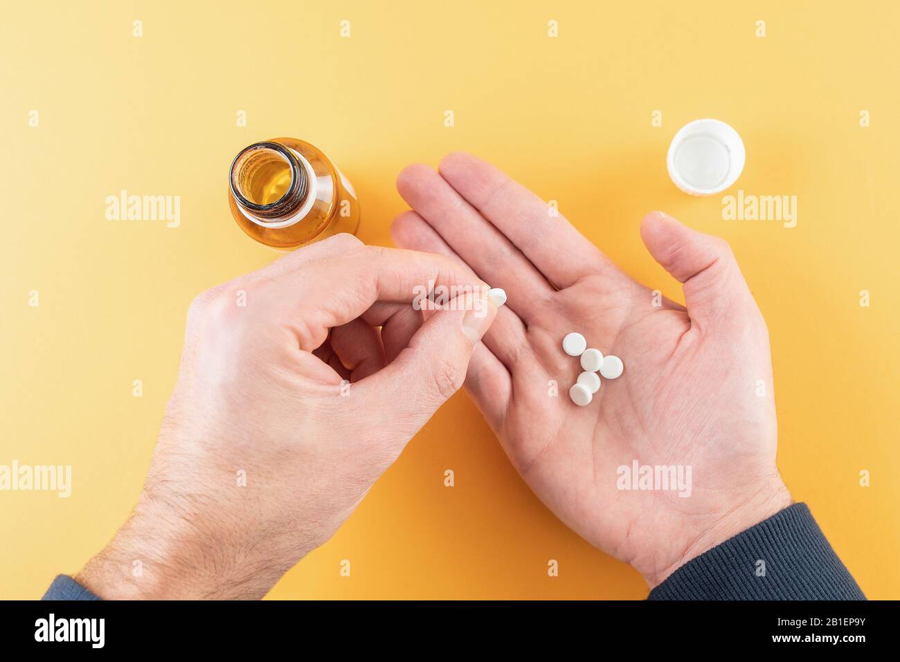 comprimés de médicament dans la paume de la main contre fond orange avec flacon de pilule Banque D'Images