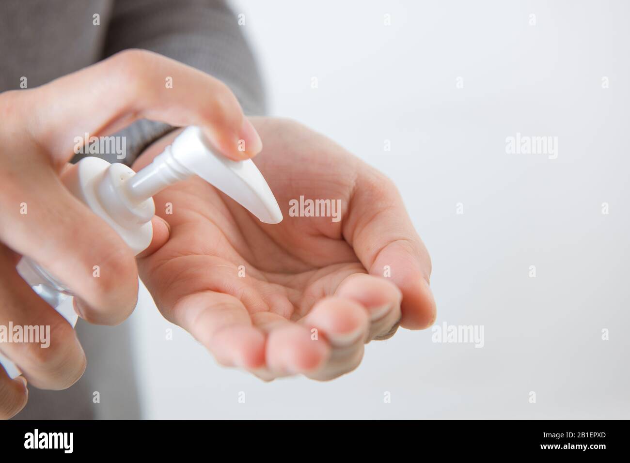 Mains féminines à l'aide de la main de lavage avec l'isolat aseptisant à l'alcool sur un fond blanc. Promouvoir les gens utiliser le masque facial pour se protéger du virus Banque D'Images