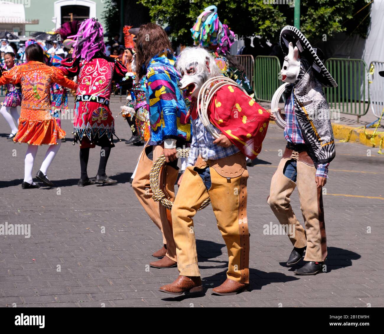 Trois danseuses en vêtements de cowboy faisant partie d'une Camada de Chivarrudos marchant la partie de plume de danse d'une Portée de Huehues en costumes mexicains traditionnels Banque D'Images