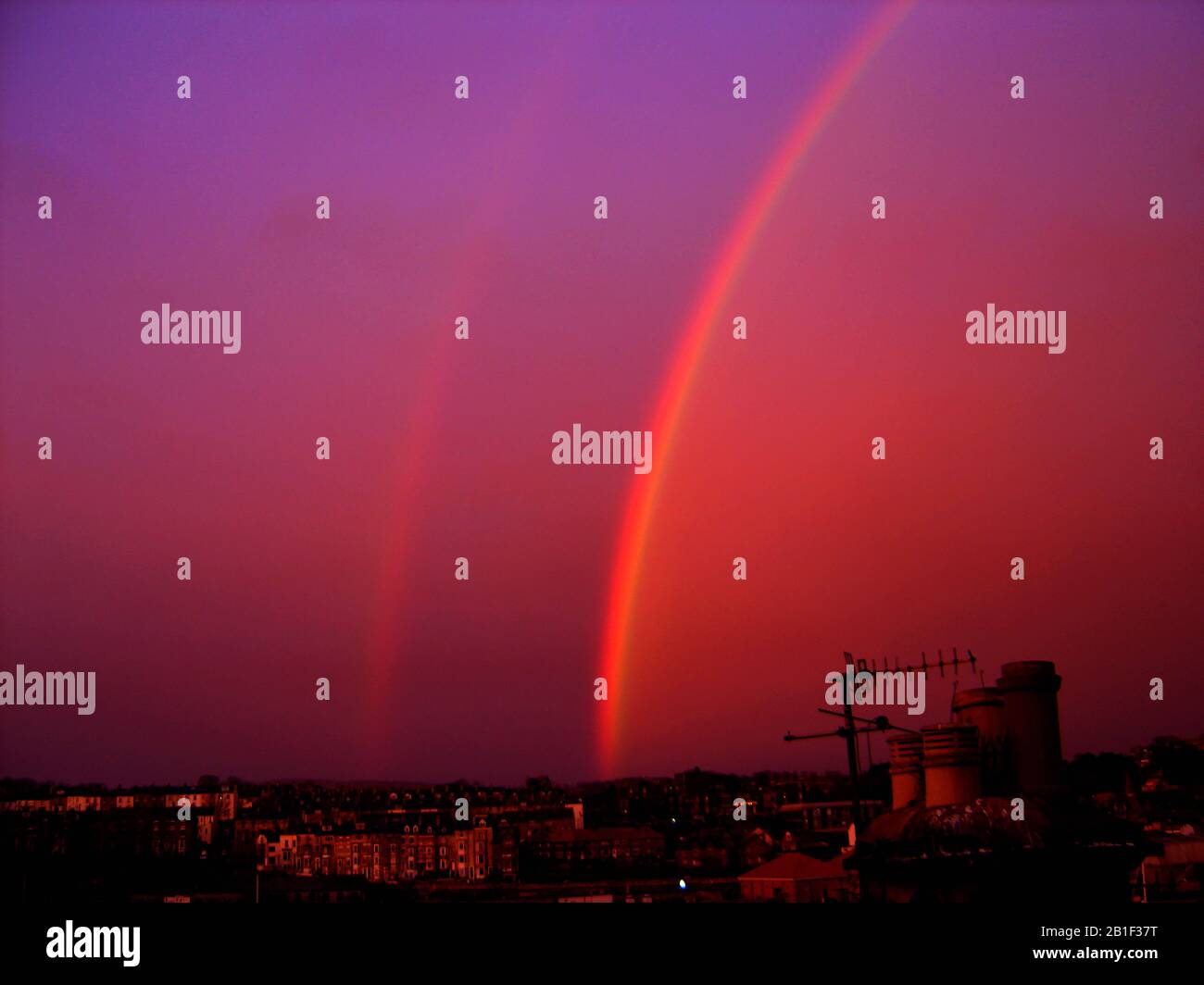 Un double arc-en-ciel spectaculaire contre un ciel mauve en colère, photographié à Whitby, dans le Yorkshire, au Royaume-Uni, en 2017. Traditionnellement, les cieux violets du soir prédisent les vents violents ou les conditions de tempête. Un arc-en-ciel du soir est appelé un arc-en-ciel lunaire. Ils ne peuvent généralement être visibles qu'à une pleine lune (ou à une lune proche). Ils sont généralement plus faibles qu'un arc-en-ciel normal , en raison de la plus petite quantité de lumière réfléchie de la surface de la lune et sont relativement rares. Un double cinet est même plus rarer. Banque D'Images