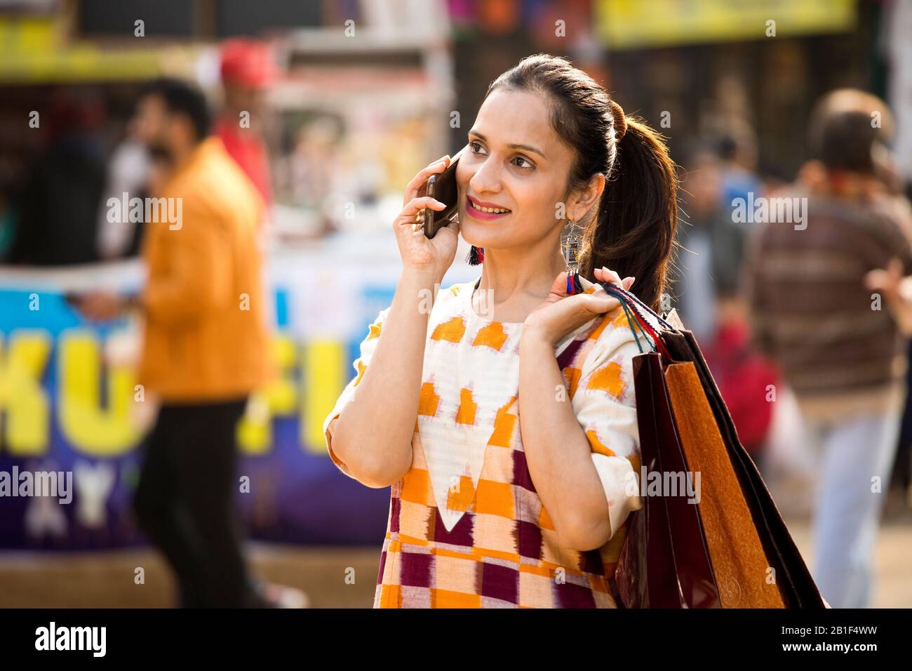 Heureuse femme tenant des sacs de shopping et parler sur le téléphone mobile sur le marché Banque D'Images