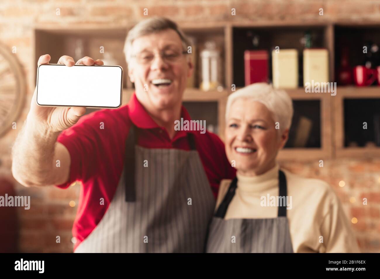 Heureux couple senior prenant selfie sur smartphone moderne avec écran blanc Banque D'Images