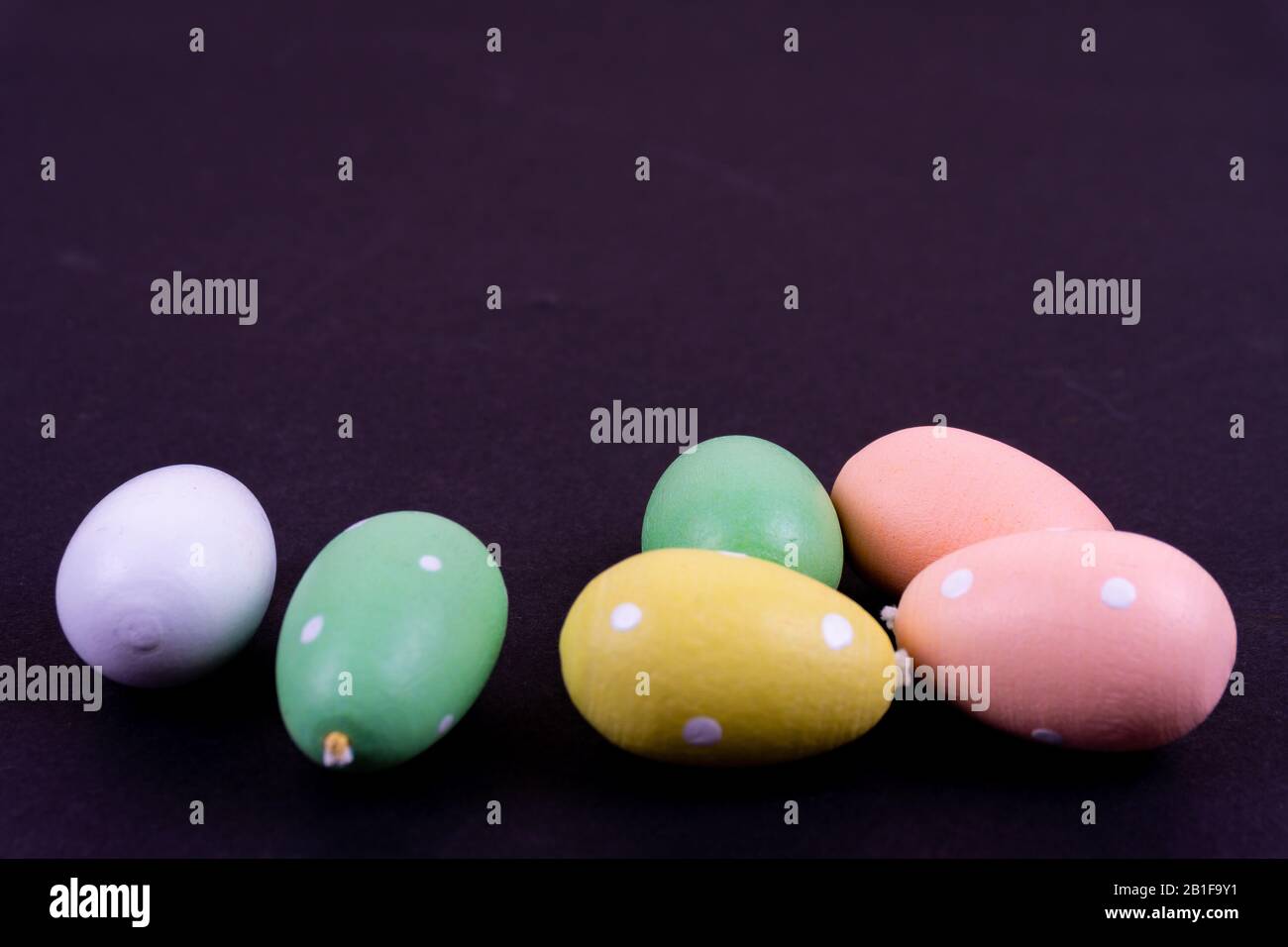 Gros plan sur quelques œufs de pâques colorés pondus sur fond noir Banque D'Images