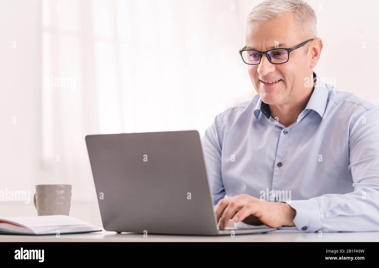 Homme senior utilisant un ordinateur portable au bureau et la saisie Banque D'Images