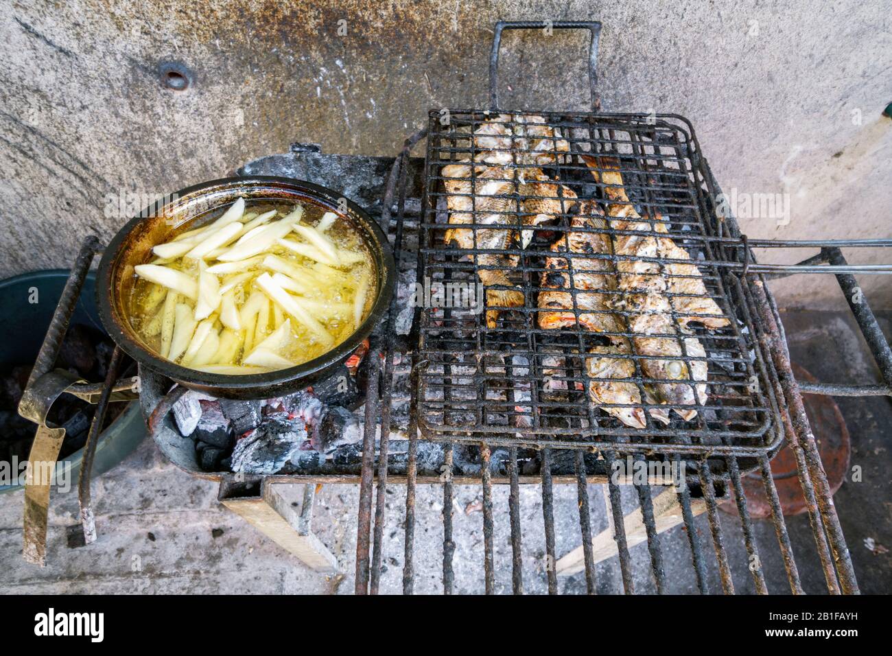 Le poisson grillé et la friture des frites au charbon de bois - une façon simple de cuisiner au Mozambique, en Afrique Banque D'Images