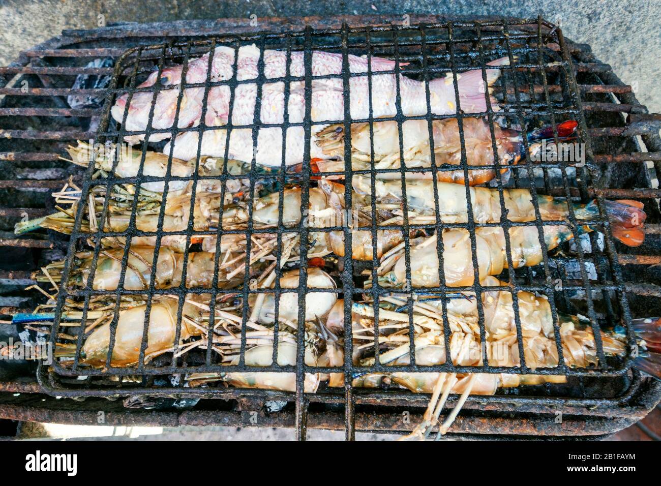 Homards grillés et poissons encore sur le feu de barbecue dans la cuisine africaine Banque D'Images