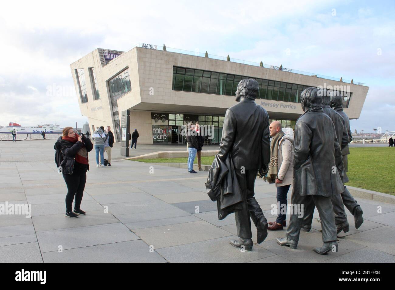 Les touristes posent avec la statue en bronze des beatles à côté du mersey à liverpool angleterre Banque D'Images