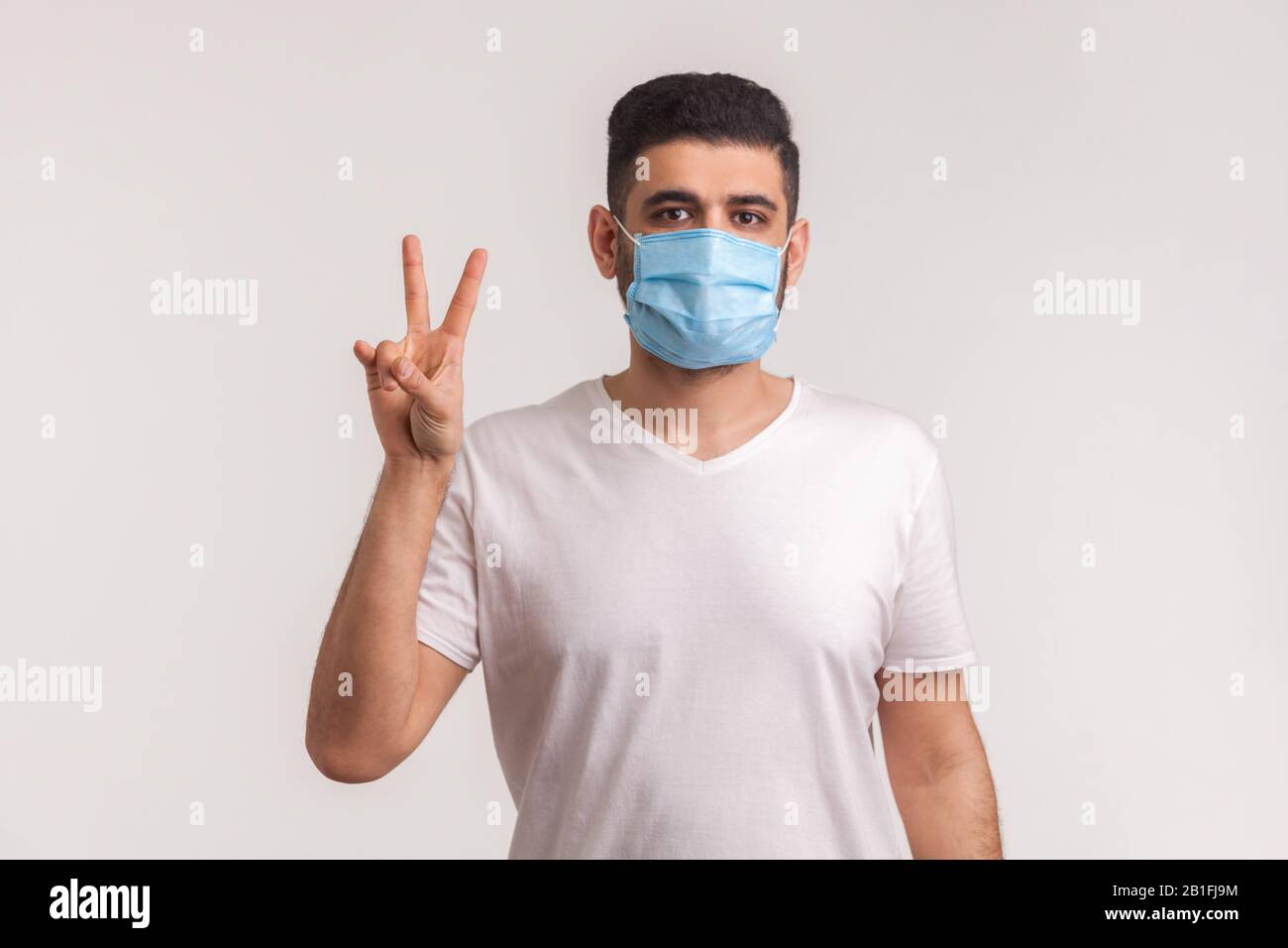 Survivant de la grippe humaine dans un masque hygiénique montrant un geste de victoire, se réjouissant de la guérison de l'infection, des maladies respiratoires telles que le coronavirus, ebola, concept Banque D'Images
