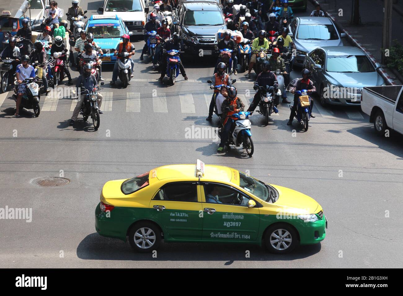 Un taxi jaune et vert et des taxis à moto à Bangkok Banque D'Images