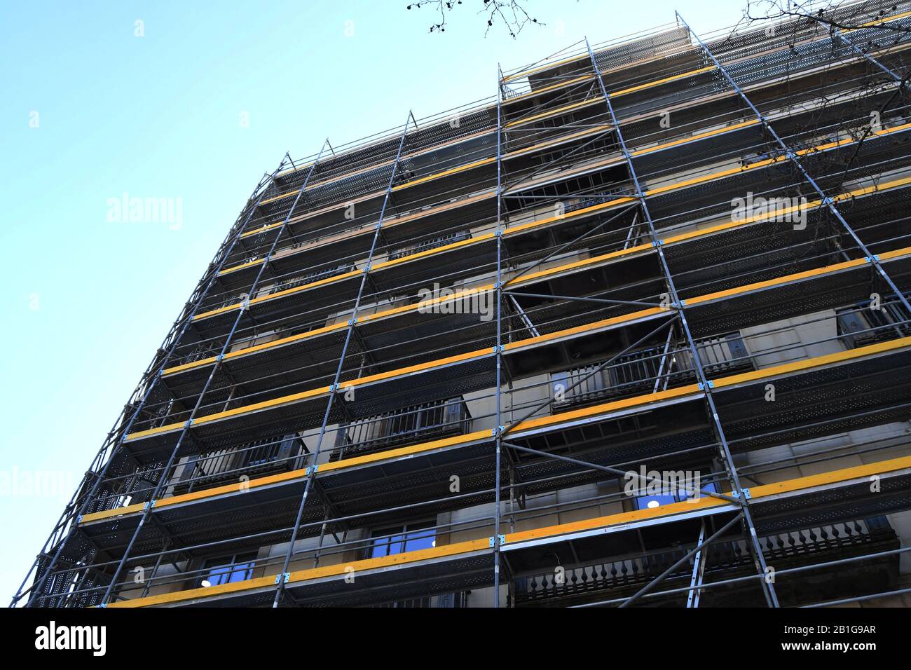 Échafaudage jaune d'un bâtiment en cours de restauration lors d'une journée ensoleillée à Barcelone Banque D'Images