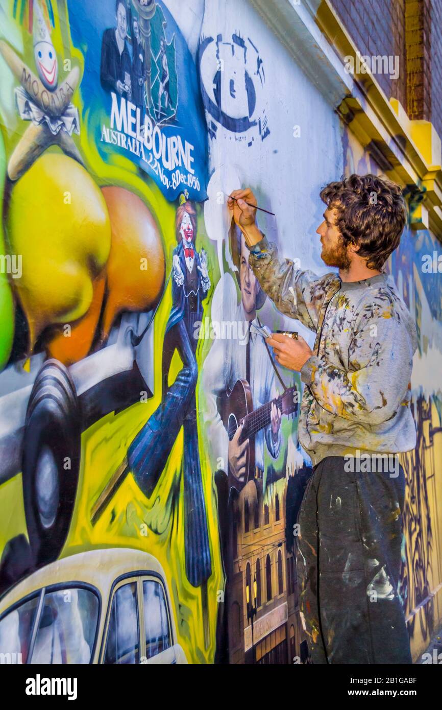 Jeune homme, artiste au travail peint une fresque représentant les thèmes emblématiques de Melbourne, Richmond, Melbourne, Victoria, Australie Banque D'Images