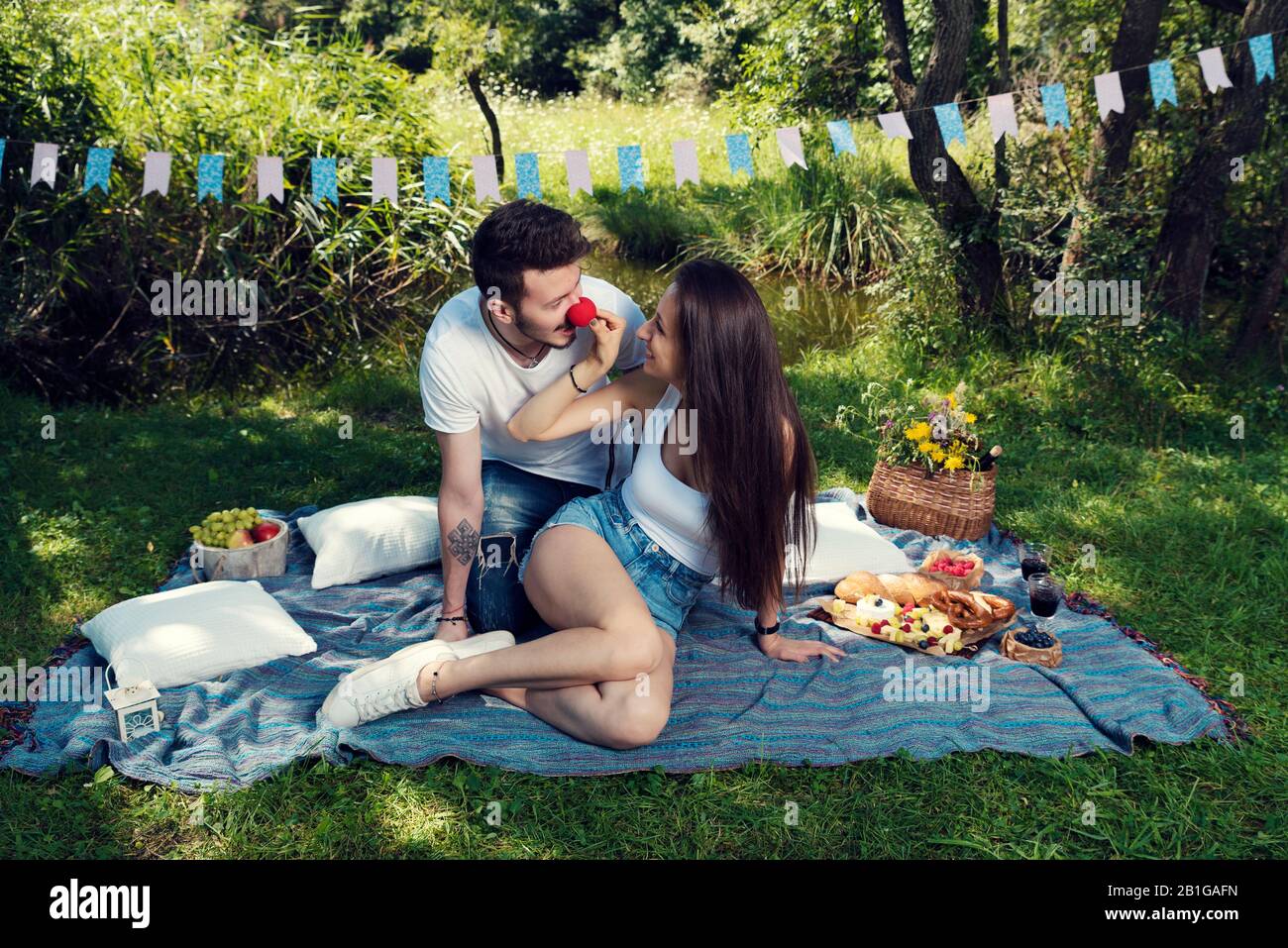 Jeune couple joueur ayant pique-nique dans le parc de la ville, Il porte le nez rouge Selective focus Banque D'Images
