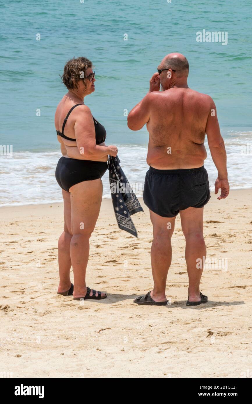 un couple d'âge moyen se tenant sur une plage de patong, thaïlande, bronzer sur la plage de sable au bord de la mer. Banque D'Images