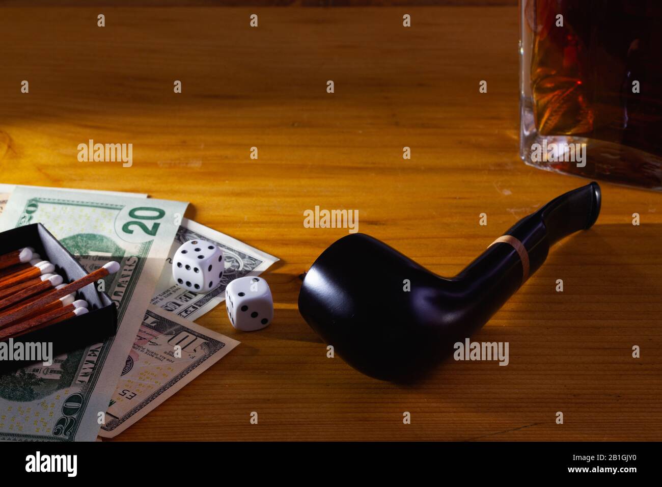 Jeux de hasard - tuyau de tabac, dés blancs, whisky écossais et billets de dollars sur la table en bois Banque D'Images