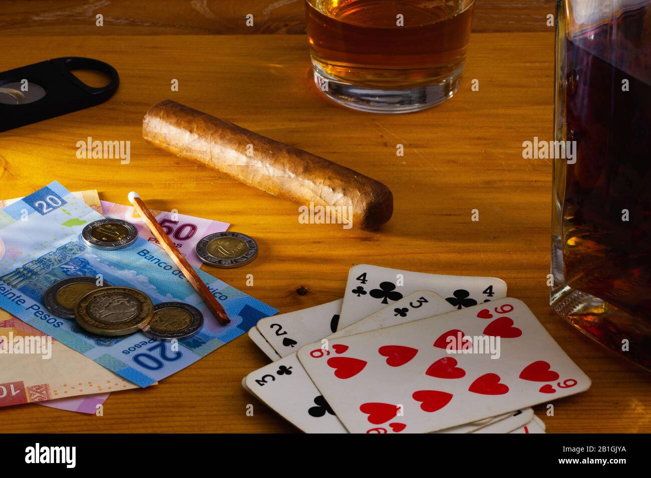 Jeu - tabac Cigar , cartes à jouer, whisky écossais et billets de banque au mexique sur la table en bois Banque D'Images