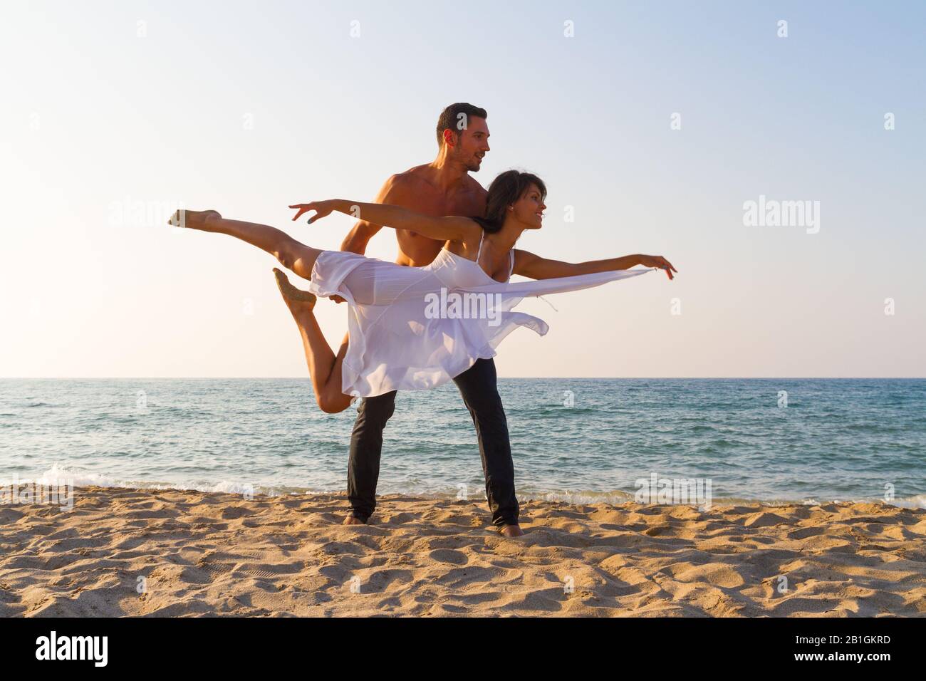 Tenue sportive jeune couple à la plage pratique des exercices de fitness acro yoga, en équilibre en couple lors d'une journée d'été au crépuscule. Style de vie sain an Banque D'Images