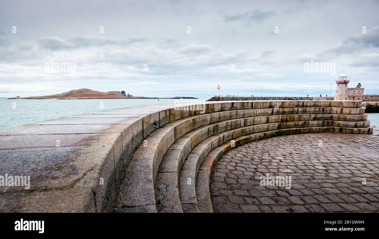 Marches en pierre incurvées devant le phare de Howth avec l'île d'Irelands Eye en arrière-plan. Temps nuageux dans le port de Howth, Dublin, Irlande Banque D'Images