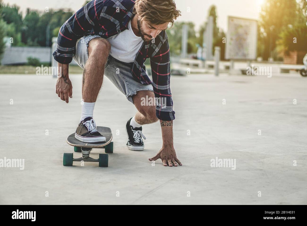 Tattoo skater en spectacle avec planche à roulettes au coucher du soleil  sur la place de la ville urbaine - Yong branché homme ayant du plaisir avec  le skateboard - concept de