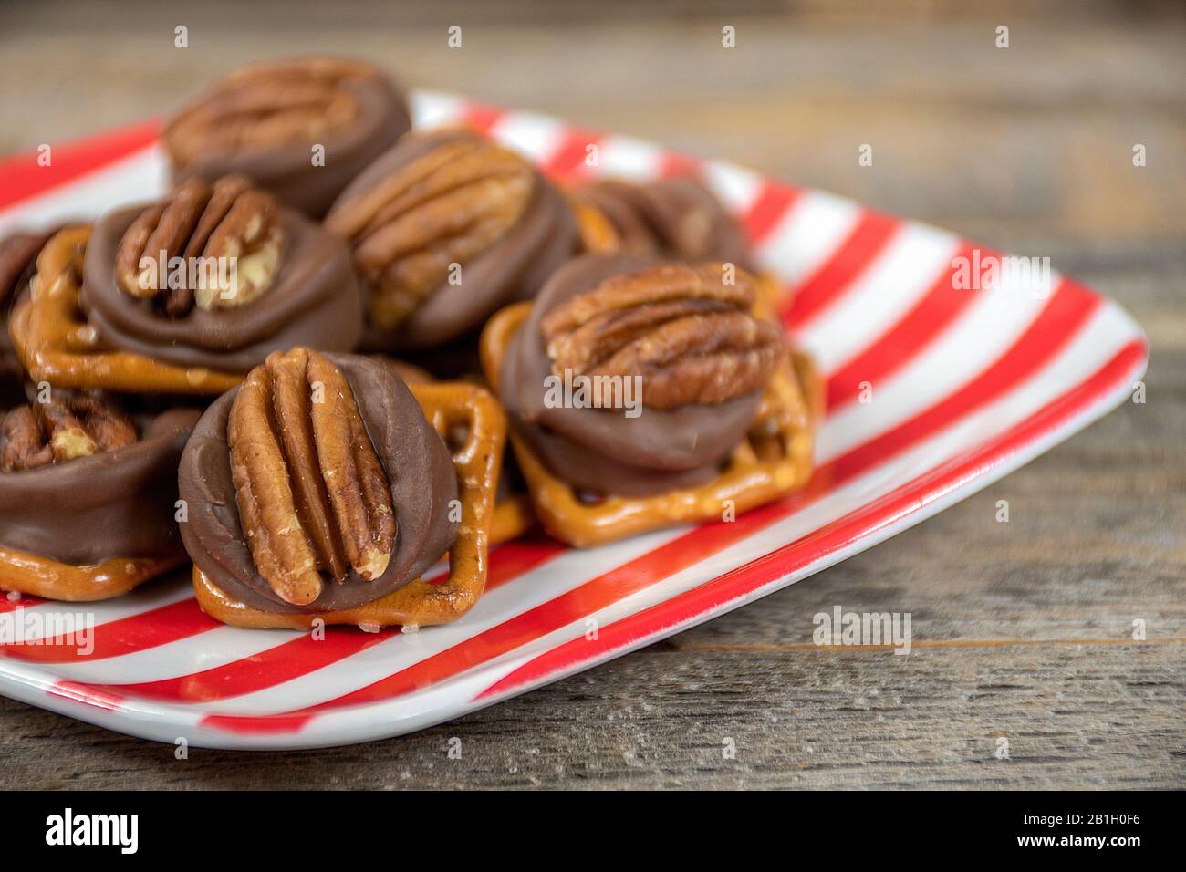 gros plan de noix de pécan et de chocolat fondu sur du bretzel salé sur une plaque rayée rouge et blanche Banque D'Images