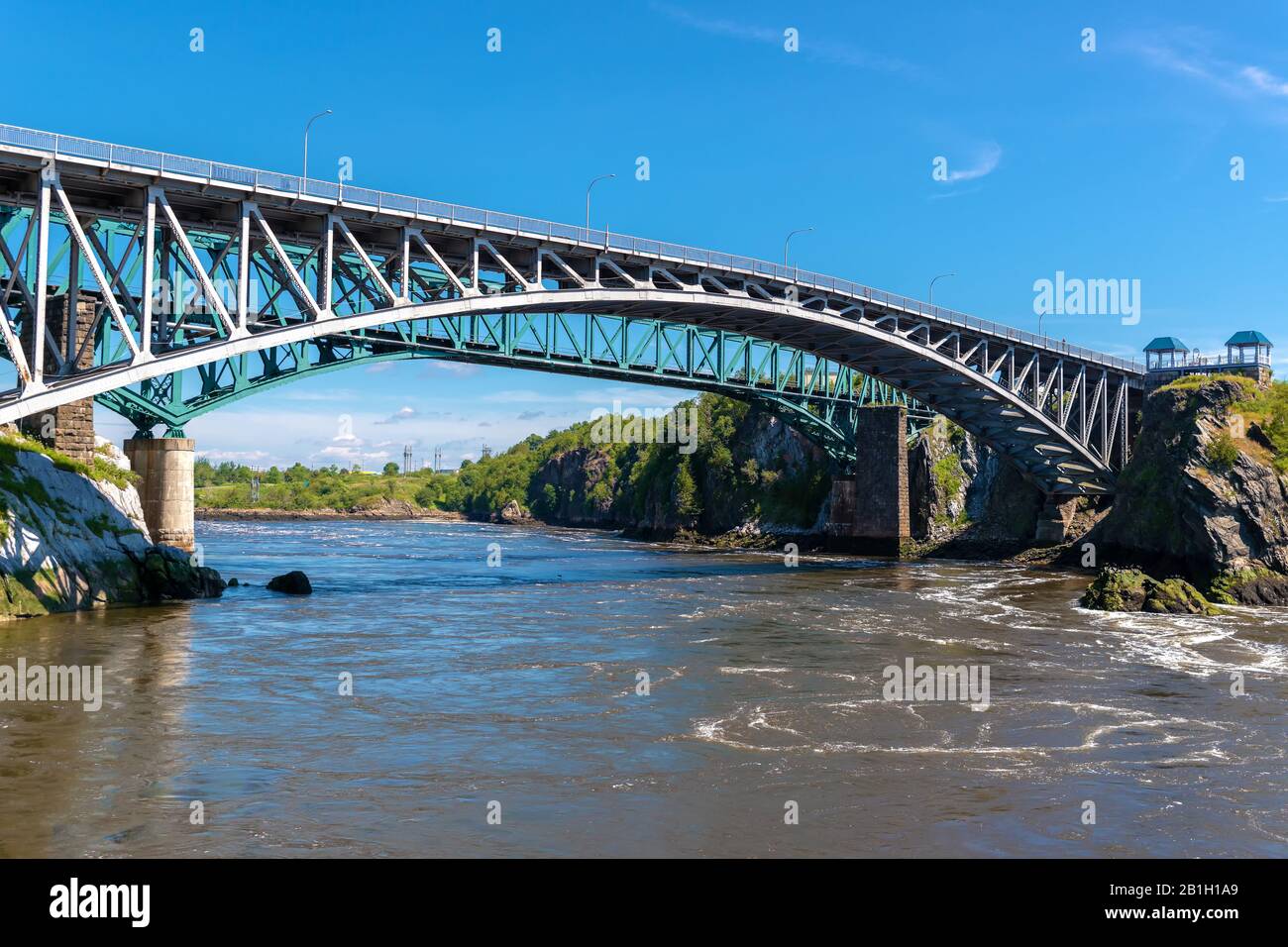 Le pont Reversing Falls à Saint John, au Nouveau-Brunswick, au Canada, au-dessus de la rivière Saint John. Rivière qui coule lentement. Pont de train derrière, ciel bleu au-dessus. Banque D'Images