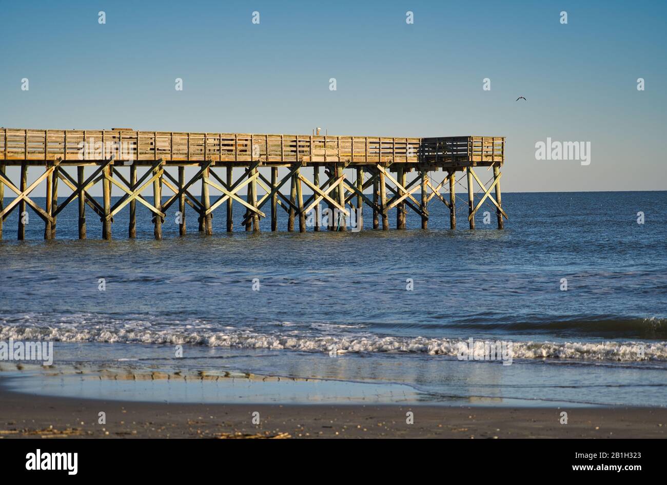 Jetée de pêche, jetée en bois qui dépasse de la mer dans l'eau avec un ciel sans nuages Banque D'Images